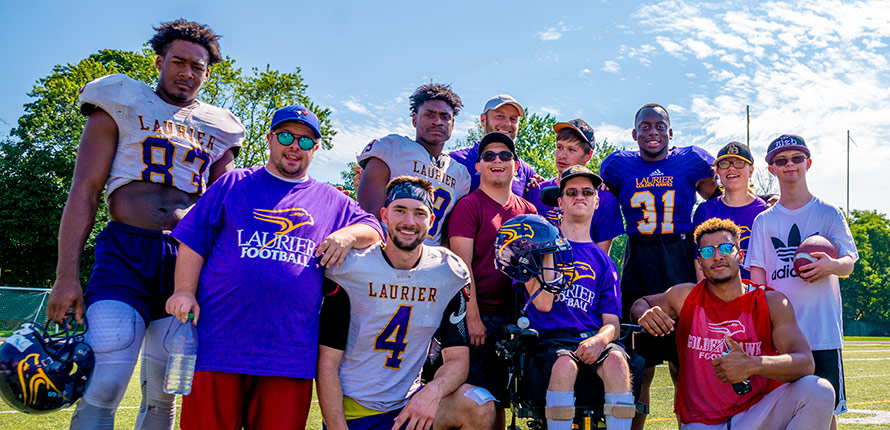Coach Faulds and Laurier football players stand with LIght House members for a picture.