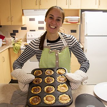 Woman holding a baking tray of butter tarts