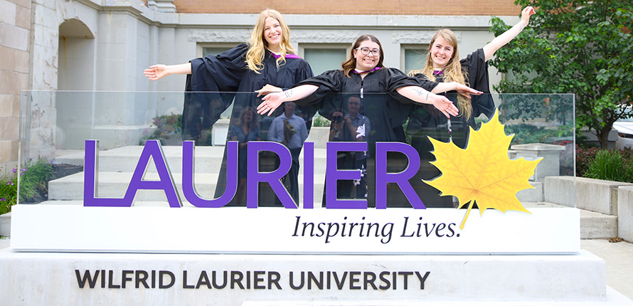 Two graduates behind Laurier lawn sign