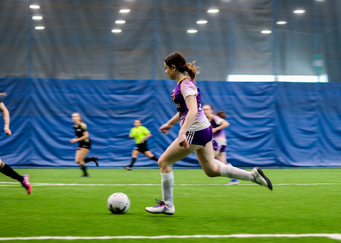 indoor soccer player running with ball during game