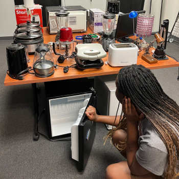 Woman crouching down to look at a mini fridge