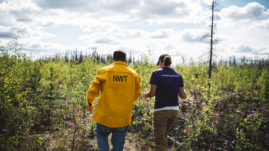 Jennifer Baltzer and Rick Olsen walking through a forest in Yellowknife