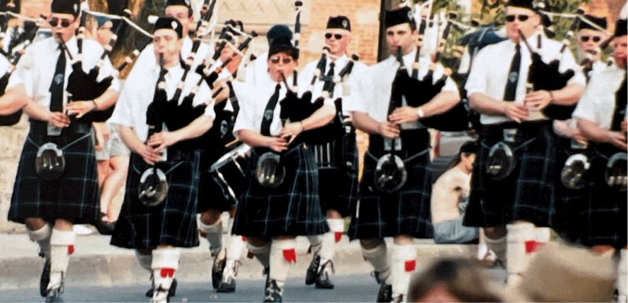 A group of bagpipers walking down a street. 