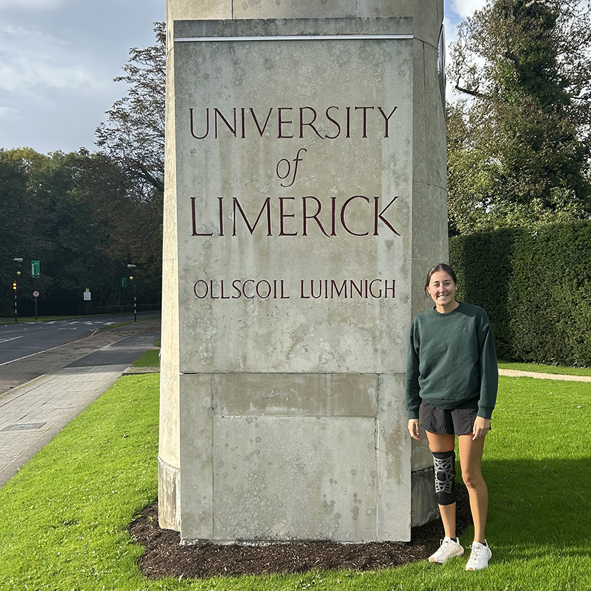 A young woman stands in front of the University of Limerick sign