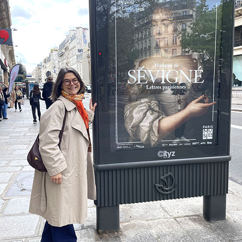 Nathalie Freidel standing in front of a poster for her museum exhibit
