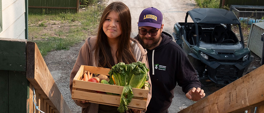 Young girl delivering produce box alongside Laurier student