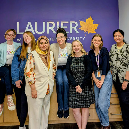Women researchers in front of Laurier sign